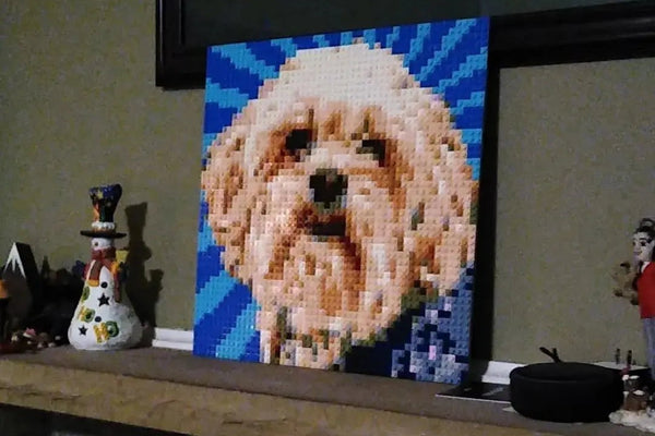 A finished brick mosaic of a fluffy white dog on a mantel with holiday decorations