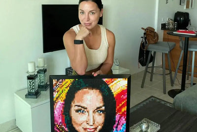 A woman at home with a finished, framed brick mosaic of her own portrait