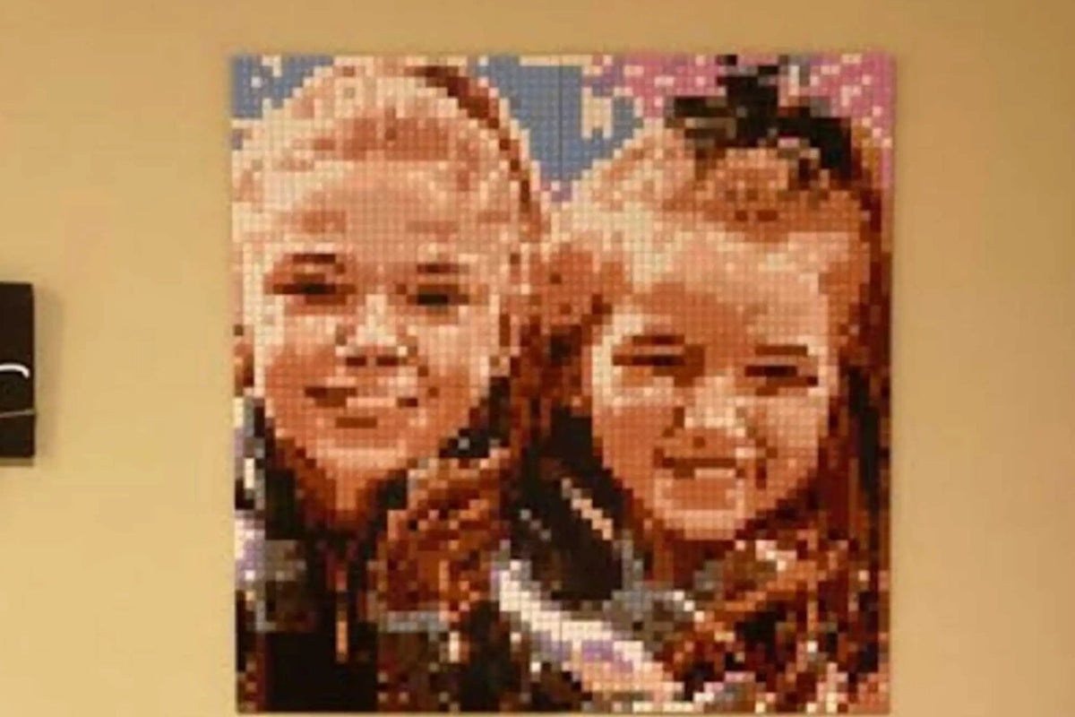 A finished brick mosaic of two smiling sisters hanging on a family room wall