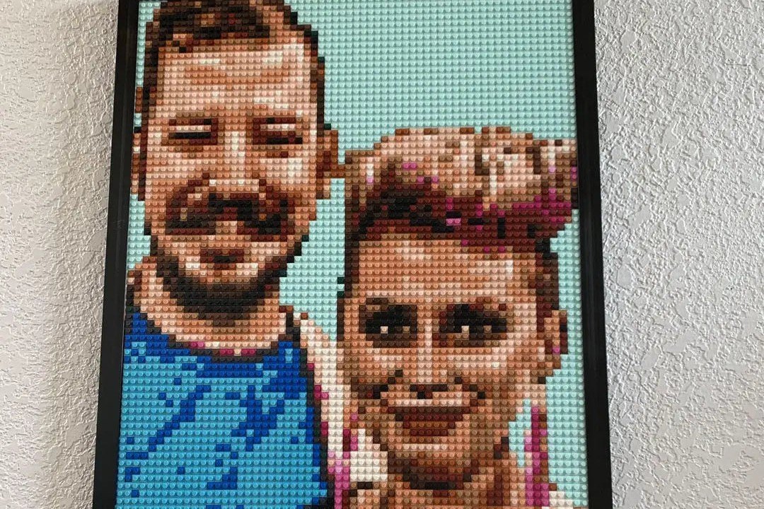 A finished brick mosaic of a smiling couple, framed and hanging on a wall